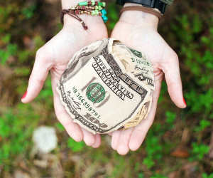 Hands holding dollars to demonstrate converting volunteers to donors